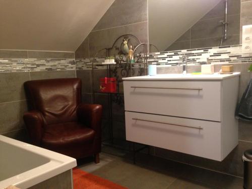 a bathroom with a sink and a brown chair at Ch. d'hôtes de la Saliais in Chavagne