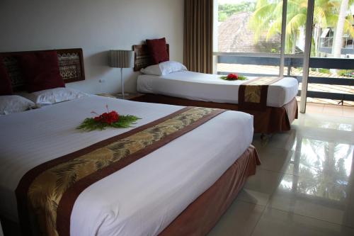 two beds in a hotel room with flowers on them at Capricorn International Hotel in Nadi