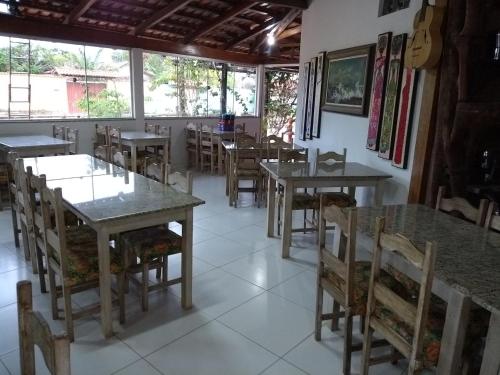 a dining room with tables and chairs and a guitar at Pousada Miosotis in Nova Viçosa