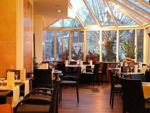 メシェデにあるVon Korff´S Rest & Relax Hotelのテーブルと椅子、大きな窓のあるレストラン