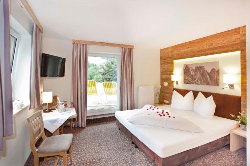 a hotel room with a bed and a desk and a window at Gasthof zum Wilden Kaiser in Scheffau am Wilden Kaiser
