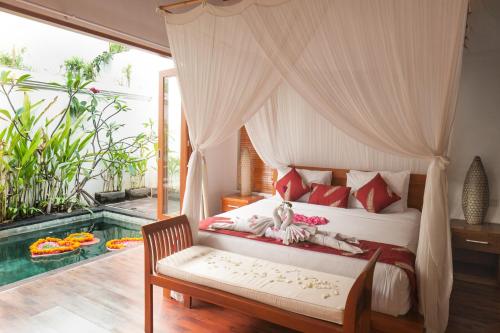 a bedroom with a canopy bed and a pool at Villa Bougainville in Seminyak