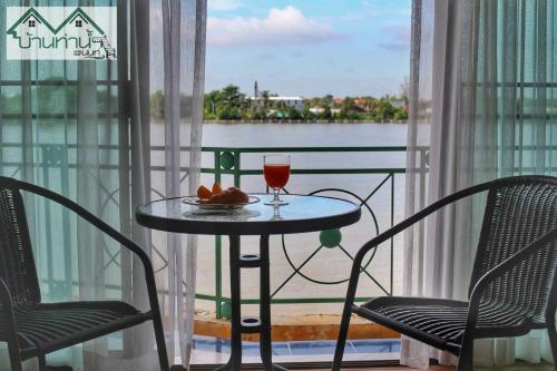 een tafel met een drankje en 2 stoelen op een balkon bij Baanthanam Nont in Nonthaburi