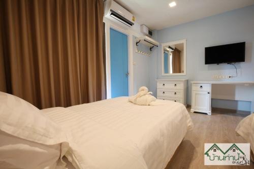 a bedroom with a white bed with a stuffed animal on it at Baanthanam Nont in Nonthaburi