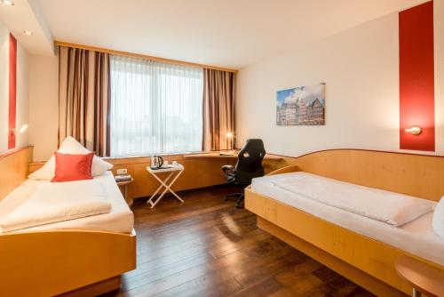 a hotel room with two beds and a desk at L'Escala in Dreieich