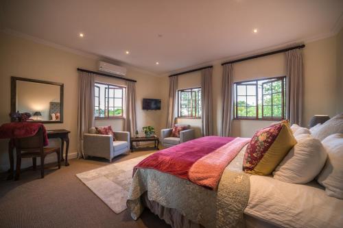 a bedroom with a bed and a desk and windows at Boutique Villa Guesthouse in Somerset West