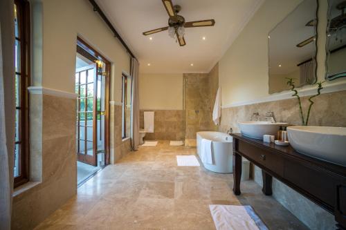 Boutique Villa Guesthouse في سومرست ويست: حمام به مغسلتين ومرآة كبيرة