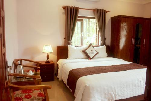 1 dormitorio con cama, ventana y silla en Loc Khang Homestay, en Hoi An