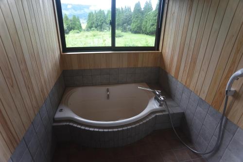 a bath tub in a bathroom with a window at Wakka in Minami Aso