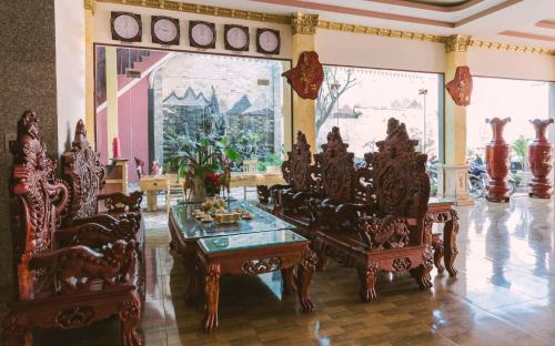 a living room with wooden chairs and a table at AEC Hotel Ban Me in Buon Ma Thuot