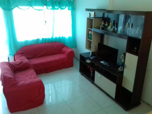 a living room with a red couch and a flat screen tv at Quartos Praia do Foguete Cabo Frio in Cabo Frio