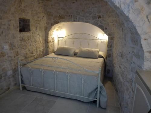 a bedroom with a bed in a stone wall at Trulli Resort Grassi in Alberobello