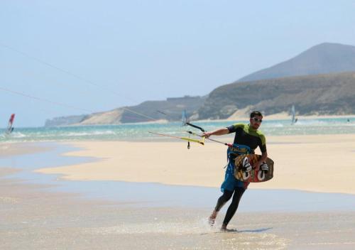 a man walking on the beach holding a kite at Your Ocean Suite in Costa Calma