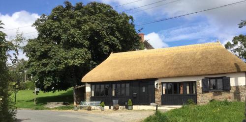 a small building with a thatched roof and a bench at The Old Coach House in Iddesleigh