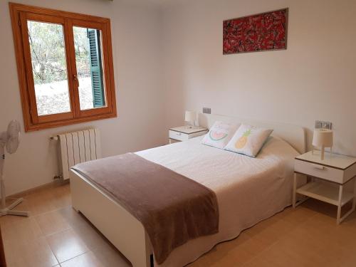a bedroom with a bed with two tables and a window at Es Closet in El Port de la Selva
