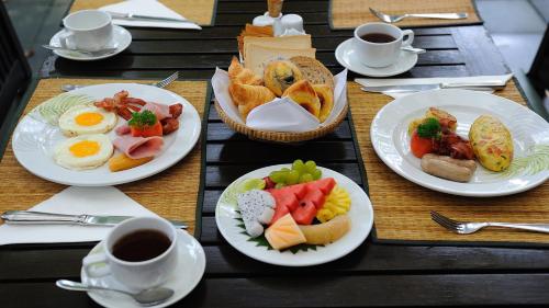 a table with plates of breakfast foods and cups of coffee at New Fairmount Hotel and Casino in Livingstone