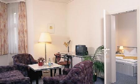 a living room with chairs and a table and a bed at Hotel - Restaurant Kurhaus Klotzsche in Dresden