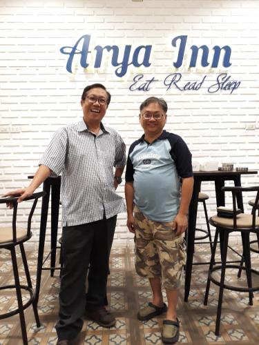 two men standing in front of a table with a sign at Arya Inn in Pematangsiantar