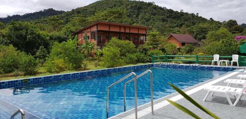 a swimming pool in front of a house with a mountain at Khao Sok Country Resort in Khao Sok National Park