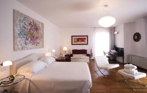 a bedroom with a white bed and a living room at Hotel Claudio in Bergeggi