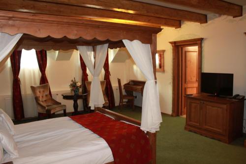 a bedroom with a canopy bed with a desk and a television at Hotel Villa Franca in Sighişoara