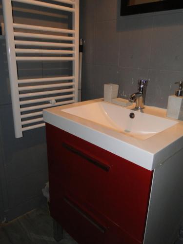 La salle de bains est pourvue d'un lavabo blanc et d'une armoire rouge. dans l'établissement Appartement NOTRE DAME, à Paris