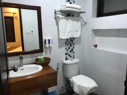 a bathroom with a sink and a toilet and a mirror at Sakaodeuan Hotel in Luang Prabang