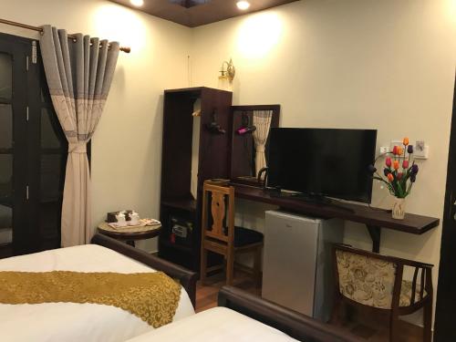 a bedroom with a bed and a flat screen tv at Sakaodeuan Hotel in Luang Prabang