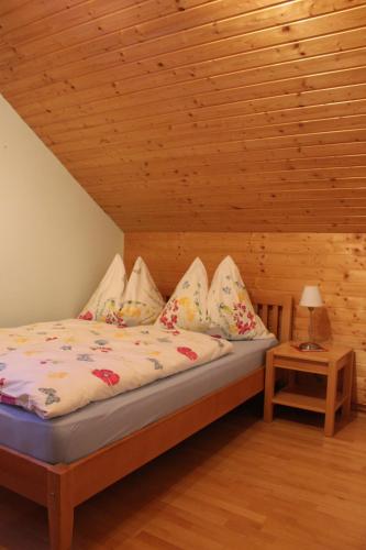 a bed in a room with a wooden ceiling at Ferienwohnungen Kolbitsch in Greifenburg