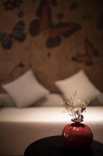 a red vase sitting on a table in front of a bed at Paco Hotel Dongpu Guanghzou -Free Shuttle Bus for Canton Fair in Guangzhou