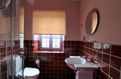 ein Bad mit einem Waschbecken, einem WC und einem Fenster in der Unterkunft Ariston in Papigko