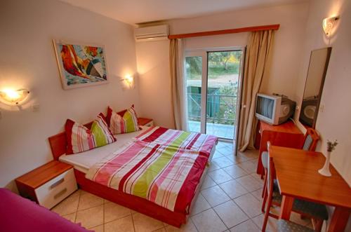 Schlafzimmer mit einem Bett, einem Tisch und einem TV in der Unterkunft Rosemary Apartments & Rooms in Mali Lošinj