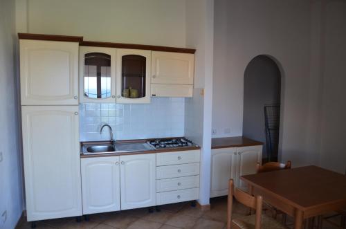 a kitchen with white cabinets and a sink and a table at Residence Costa Del Turchese in Badesi