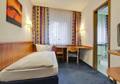 Habitación de hotel con cama y escritorio en Hotel am Friedensplatz en Stuttgart