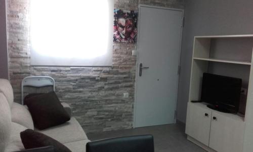 uma sala de estar com um sofá e uma televisão em Apartamento Ebro em Teruel