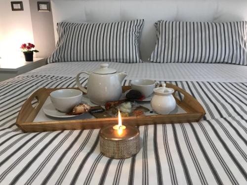 a tray with a tea set on a bed with a candle at Sweet Home Roma in Rome