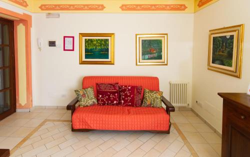 an orange couch in a room with paintings on the wall at Residenze L'Uncinaia Holiday House in Perugia