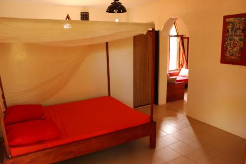 a room with a red bed with a canopy at Le Lodge Dalaal Diam in Somone