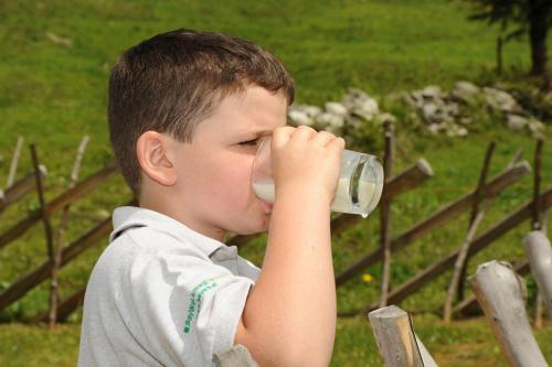 Ein kleiner Junge, der einen Drink aus einer Tasse trinkt. in der Unterkunft Hof im Feld in Schruns-Tschagguns