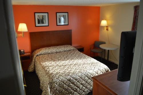Habitación de hotel con cama y paredes de color naranja en Royal Inn Motel en Watertown