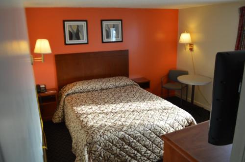 a hotel room with a bed and orange walls at Royal Inn Motel in Watertown