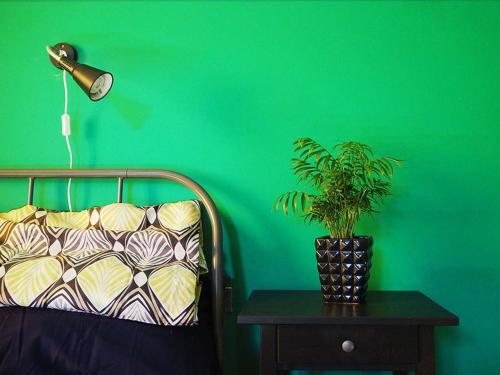 a green wall with a lamp and a plant on a table at B&b Arco Etrusco in Perugia