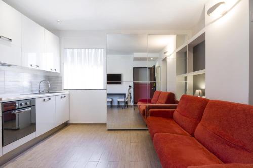 Il comprend un salon avec un canapé rouge et une cuisine. dans l'établissement PrimoPiano - Melzo A, à Milan