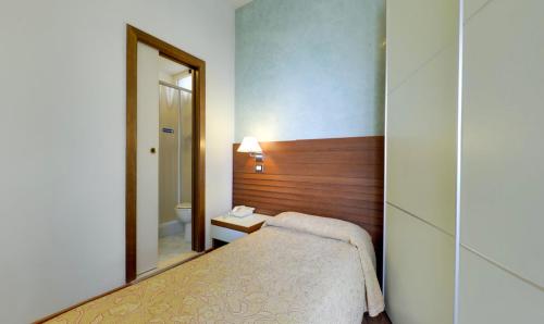 a small bedroom with a bed and a mirror at Hotel Margareth in Riccione
