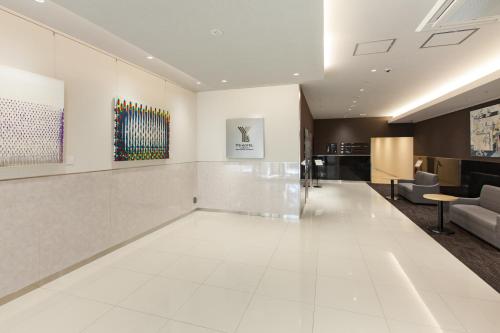 a lobby with white floors and art on the walls at Y's HOTEL Hanshin Amagasaki Ekimae in Amagasaki