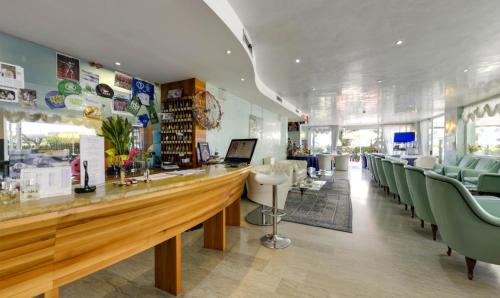 a restaurant with a bar with green chairs at Hotel Margareth in Riccione