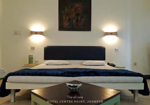 a bed in a room with two lights on the wall at Hotel Centre Point in Jodhpur