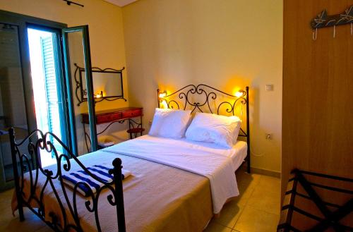 a bedroom with a bed with white sheets and a mirror at Akti Kamares in Kamáres