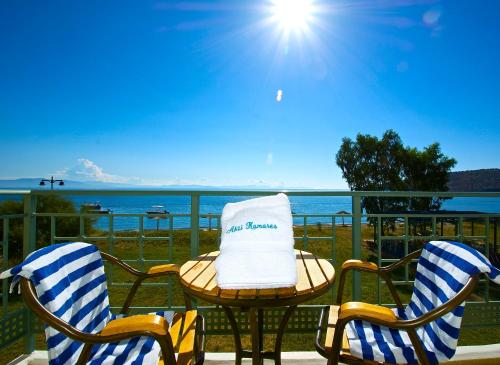 two chairs and a table on a balcony with the ocean at Akti Kamares in Kamáres