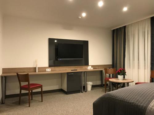 a hotel room with a desk with a television on the wall at Pension Scheiber Hof in Neunkirchen